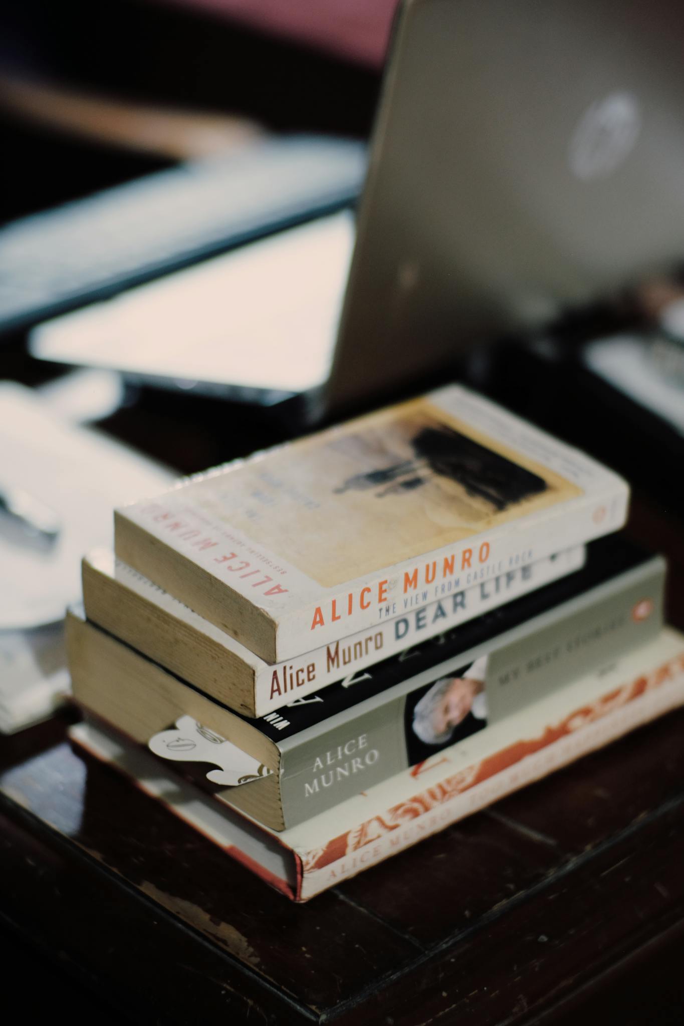 A stack of books on a wooden table with a blurred background.