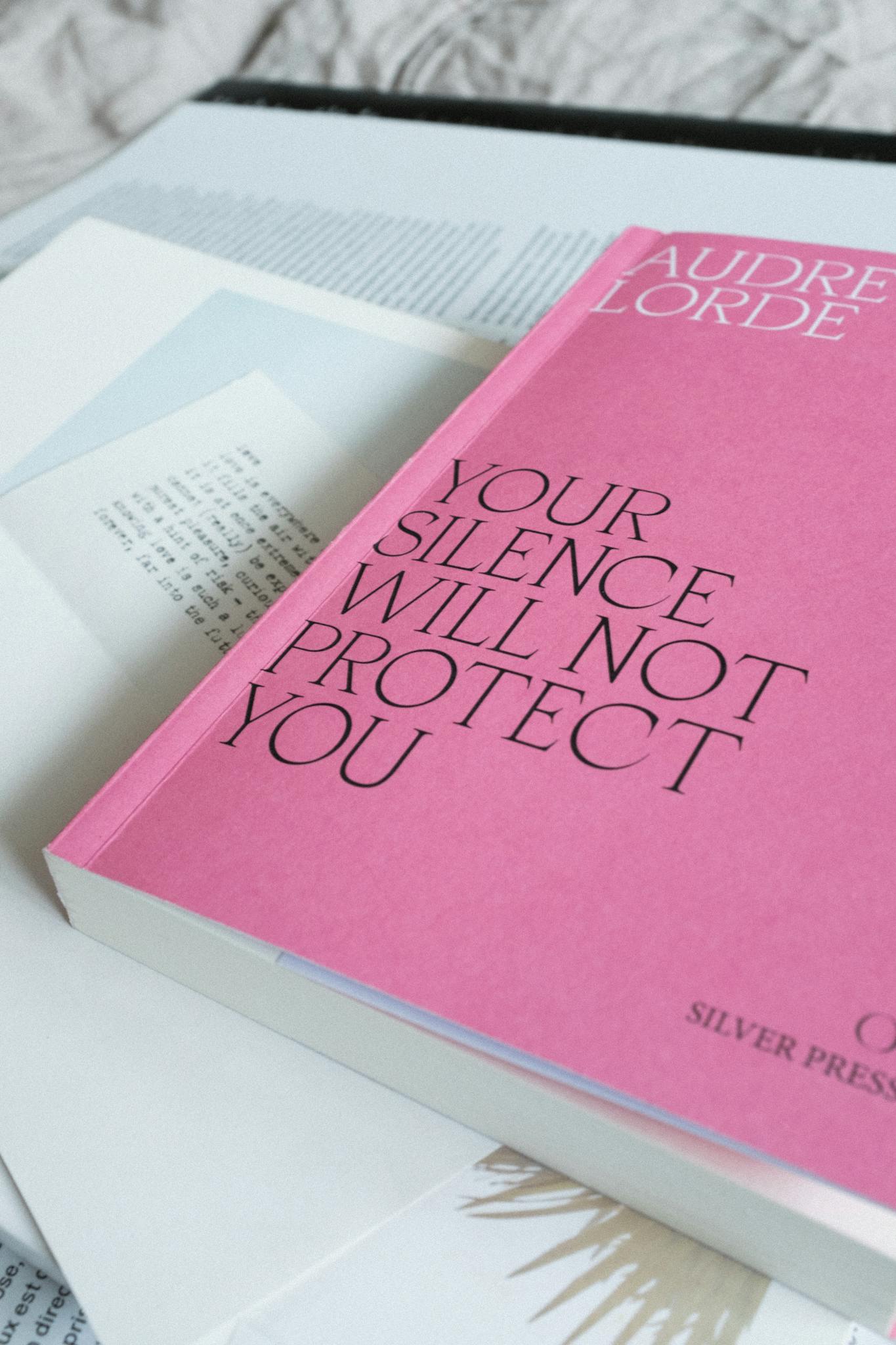 From above of book in pink soft binding lying at table among assorted papers